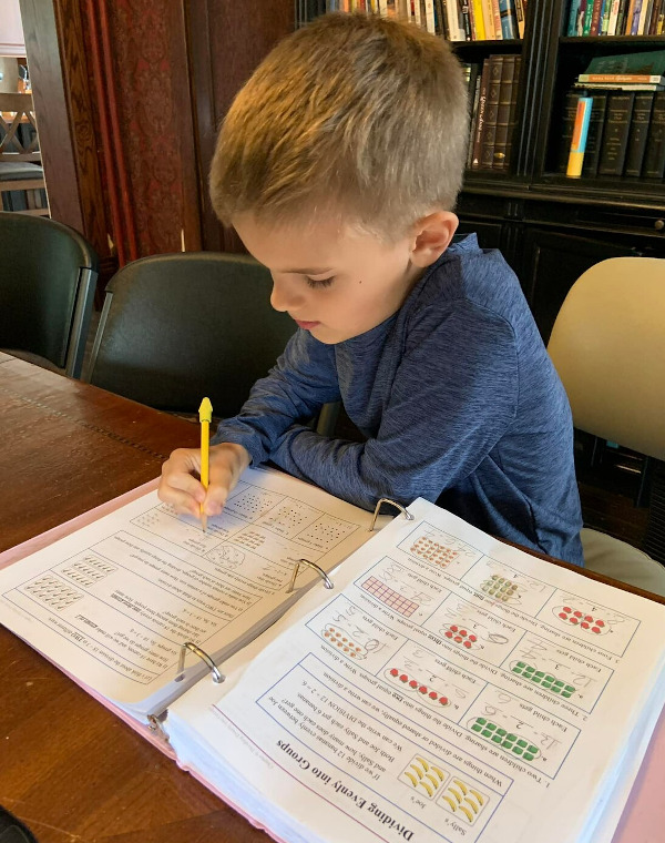 Enjoying Math Mammot work - grade 3 - Dividing Evenly into Groups Boy working on math pages